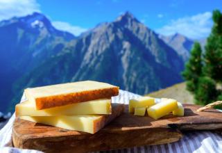 Une planche de fromage Comté AOP devant les montagnes du Jura en arrière-plan