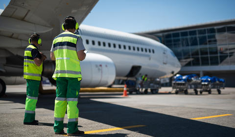 Deux agents aéroportuaires au travail sur le tarmac d'un aéroport.
